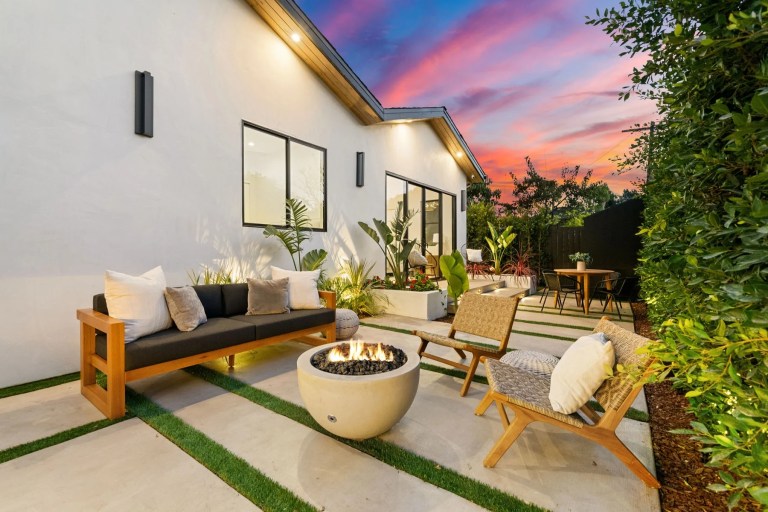 Landscaped patio at sunset with a lit fire bowl and outdoor seating