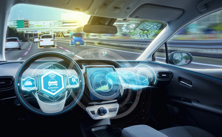 Car interior with futuristic head-up display graphics showing autonomous driving mode