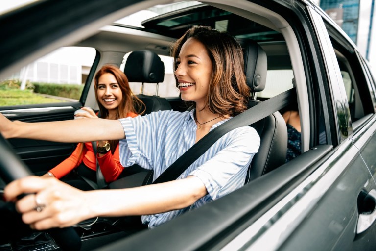Two women smiling in the front seats of a car