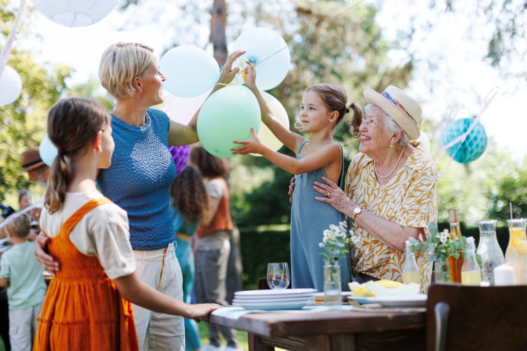 Three generations celebrating with balloons at an outdoor garden party