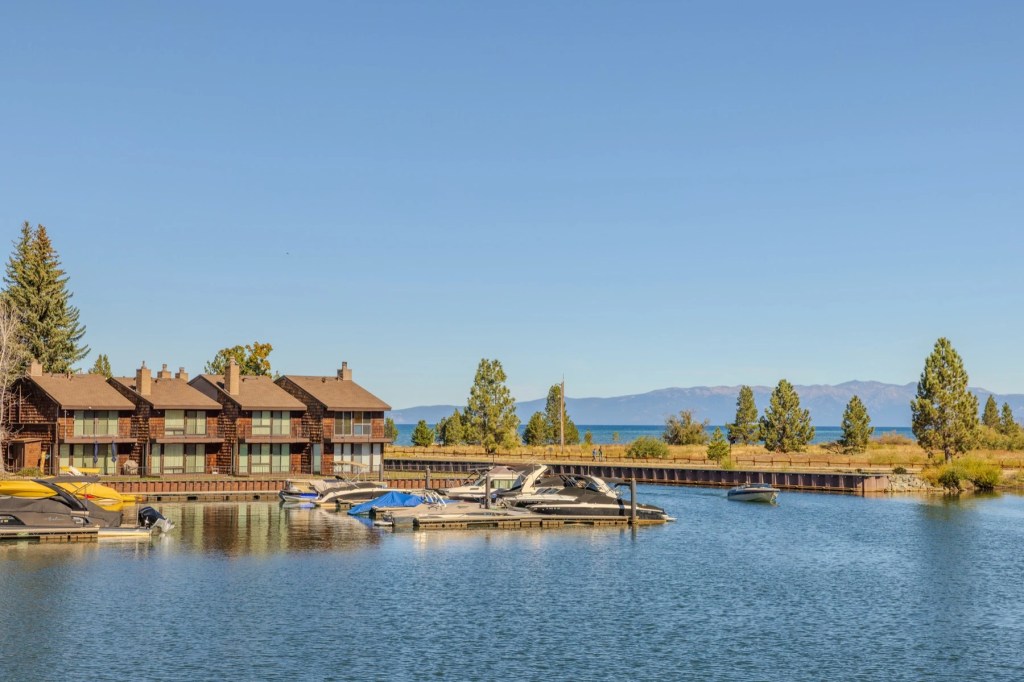 Lakeside townhouses and a marina full of moored boats under a clear sky