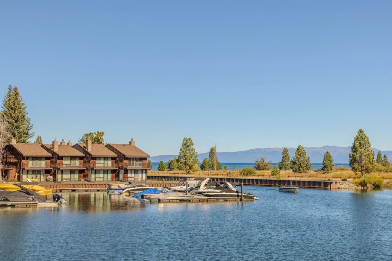 Lakeside townhouses and a marina full of moored boats under a clear sky