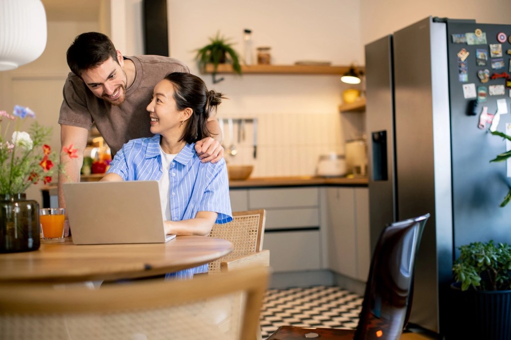 Couple looking at a laptop together at a kitchen table