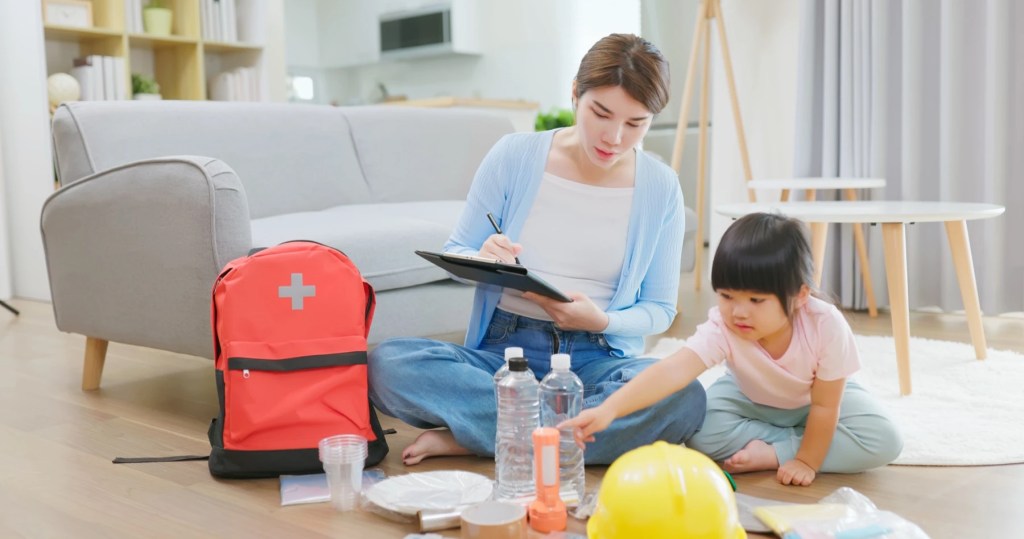 Woman and child assembling an emergency kit with a first aid backpack and flashlight