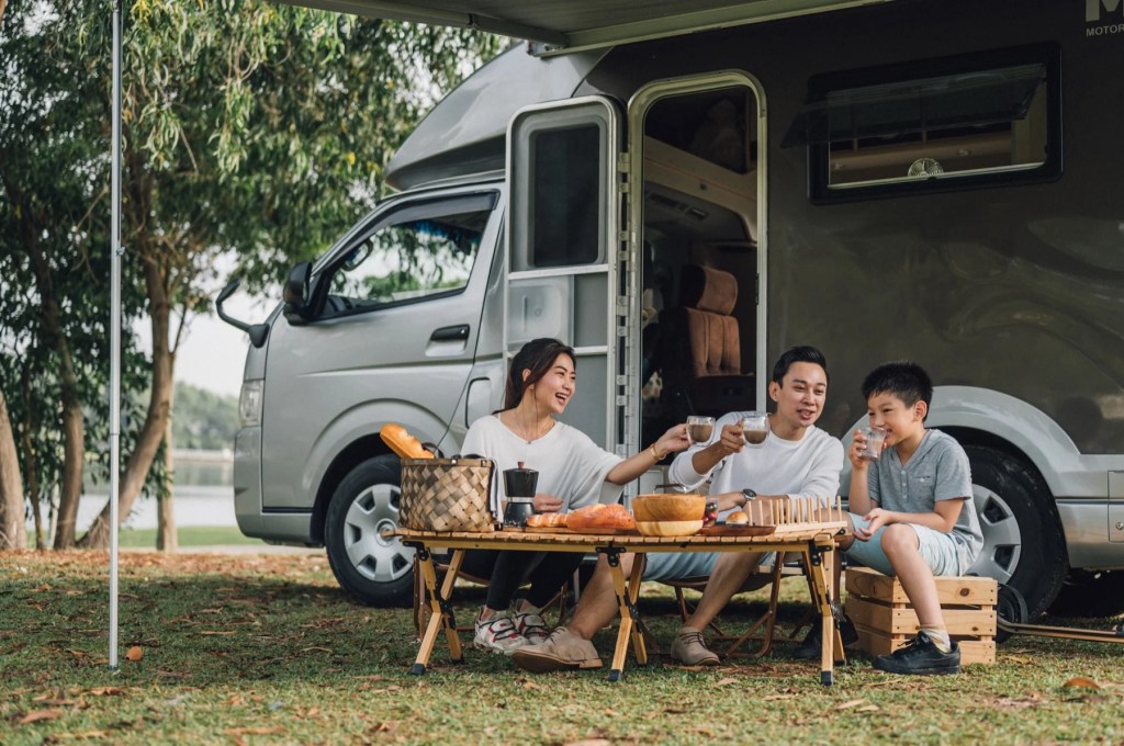 Family having coffee at a folding table beside their motorhome