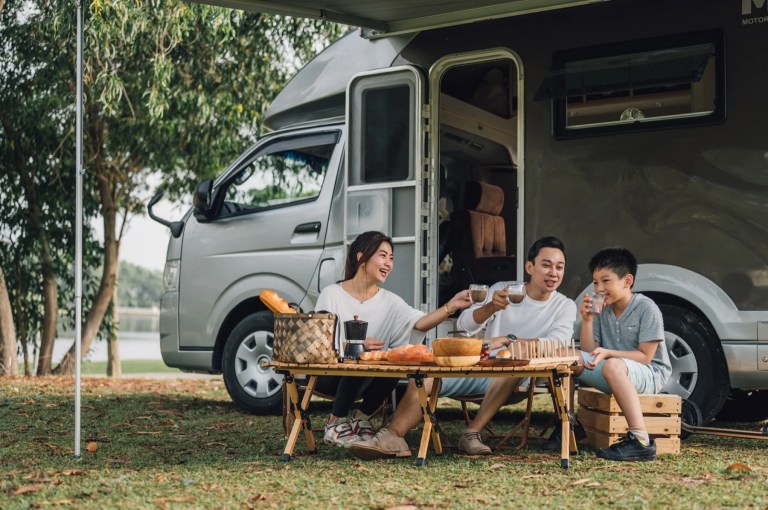 Family having coffee at a folding table beside their motorhome